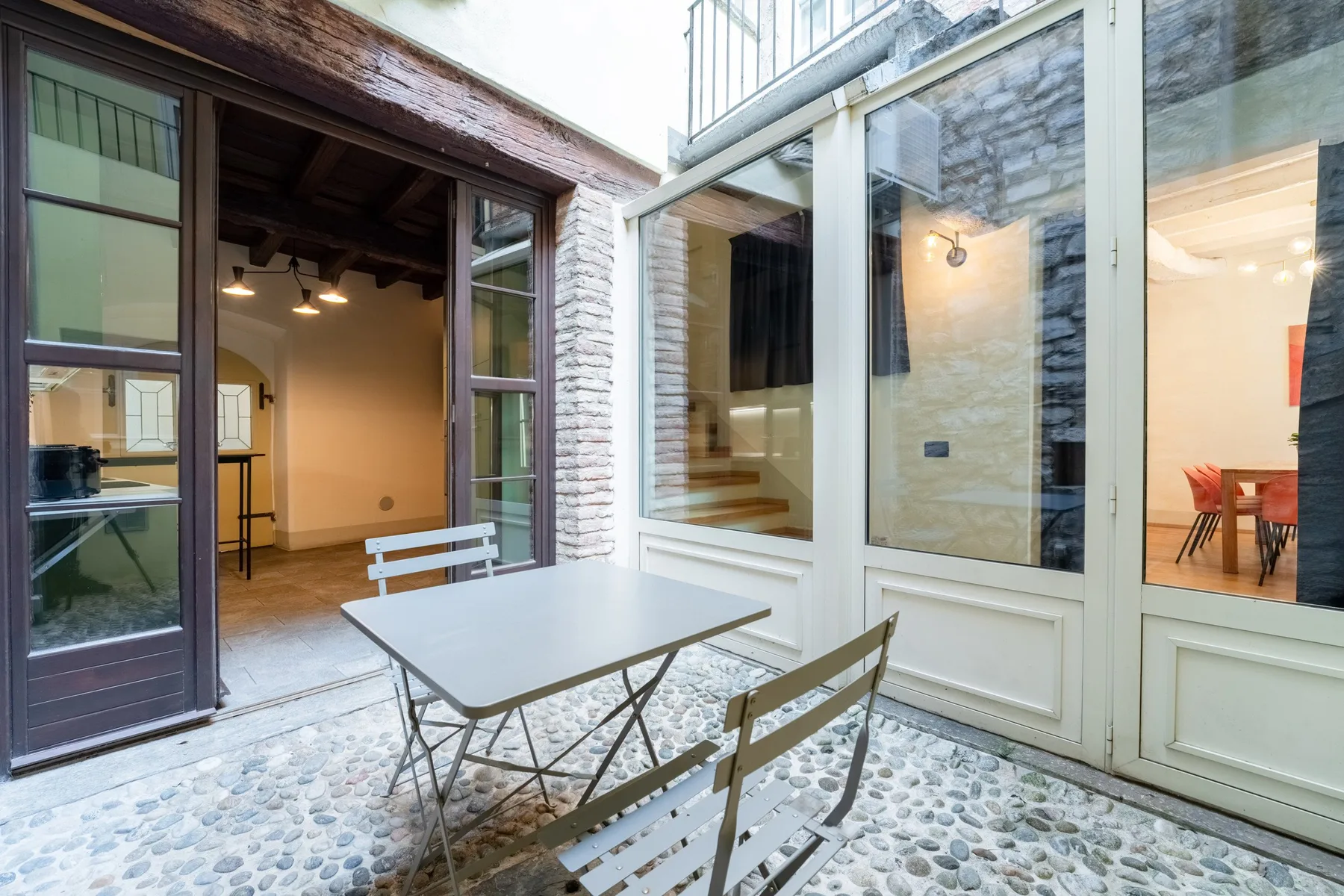 Una zona de estar en un patio con una mesa junto a grandes puertas de vidrio.