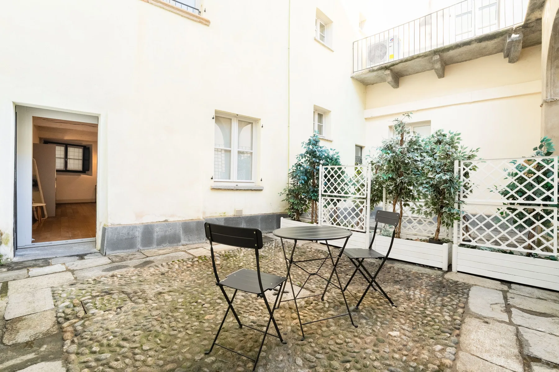 Un patio con una mesa redonda y sillas sobre un suelo empedrado.