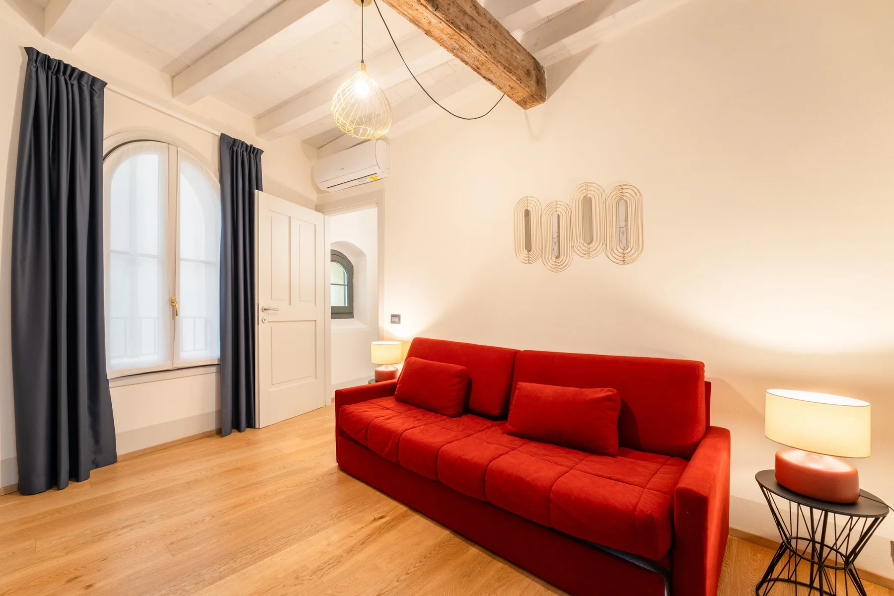 Una sala luminosa con asientos rojos, ventanas altas y vigas expuestas en el techo.