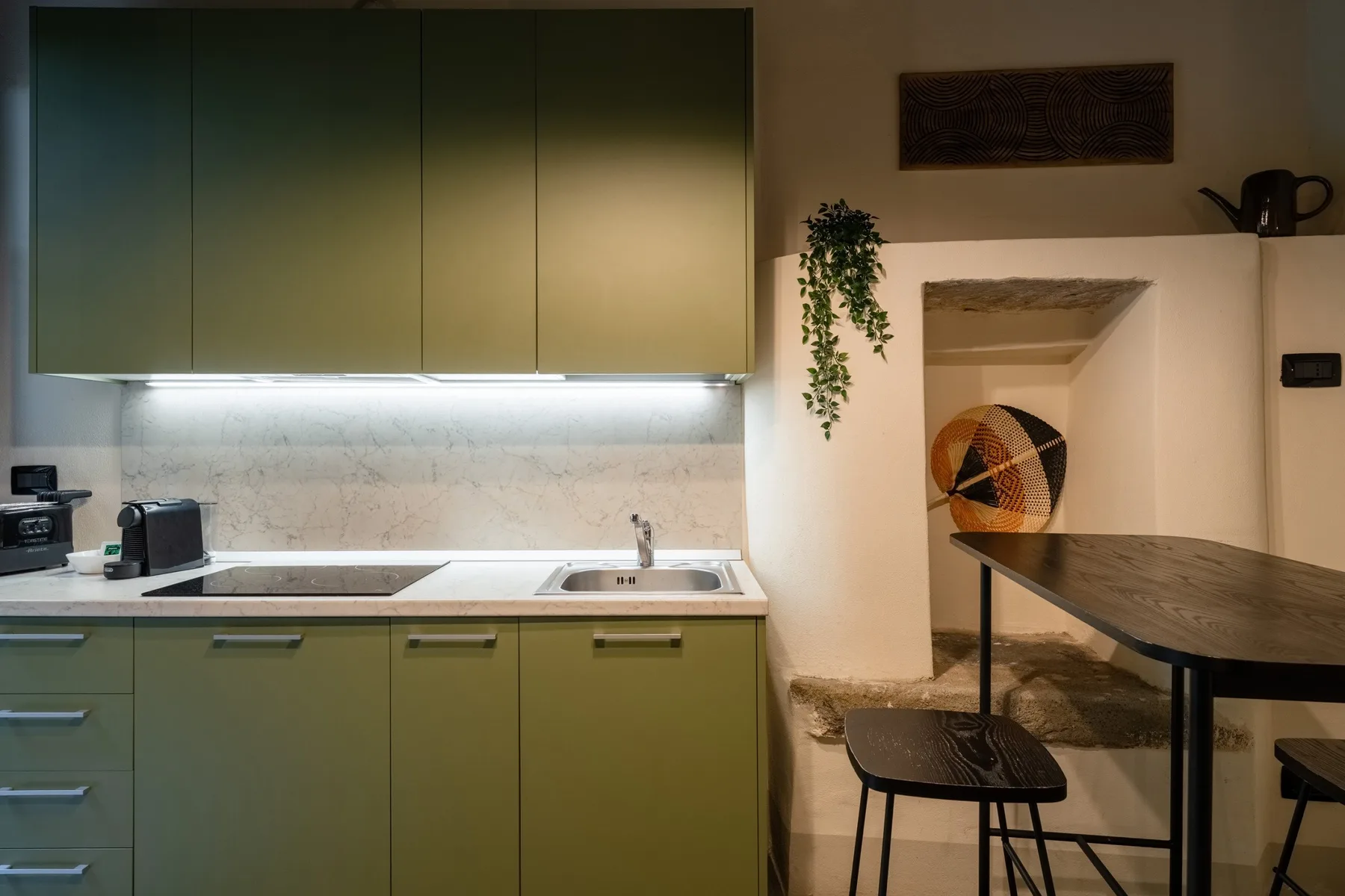 Una cocina compacta con gabinetes verdes, una encimera y una mesa de comedor.