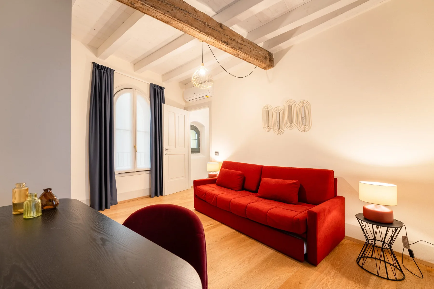 Una sala luminosa con asientos rojos, una mesa oscura y una viga de madera en el techo.