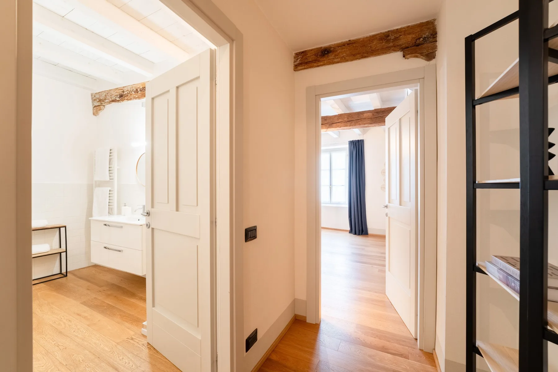 Un pasillo interior luminoso conecta un baño con una habitación soleada.