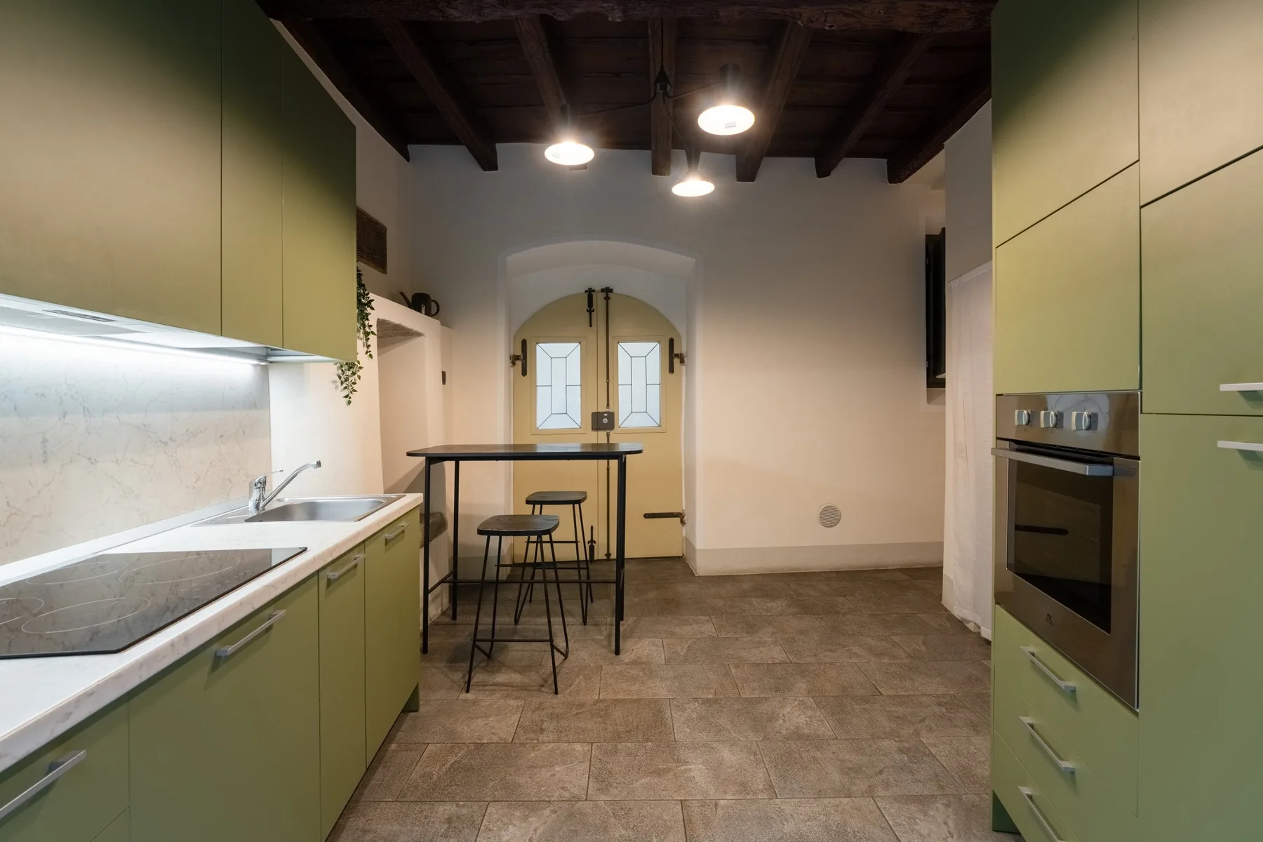Una cocina con gabinetes verdes, una encimera y una mesa pequeña.