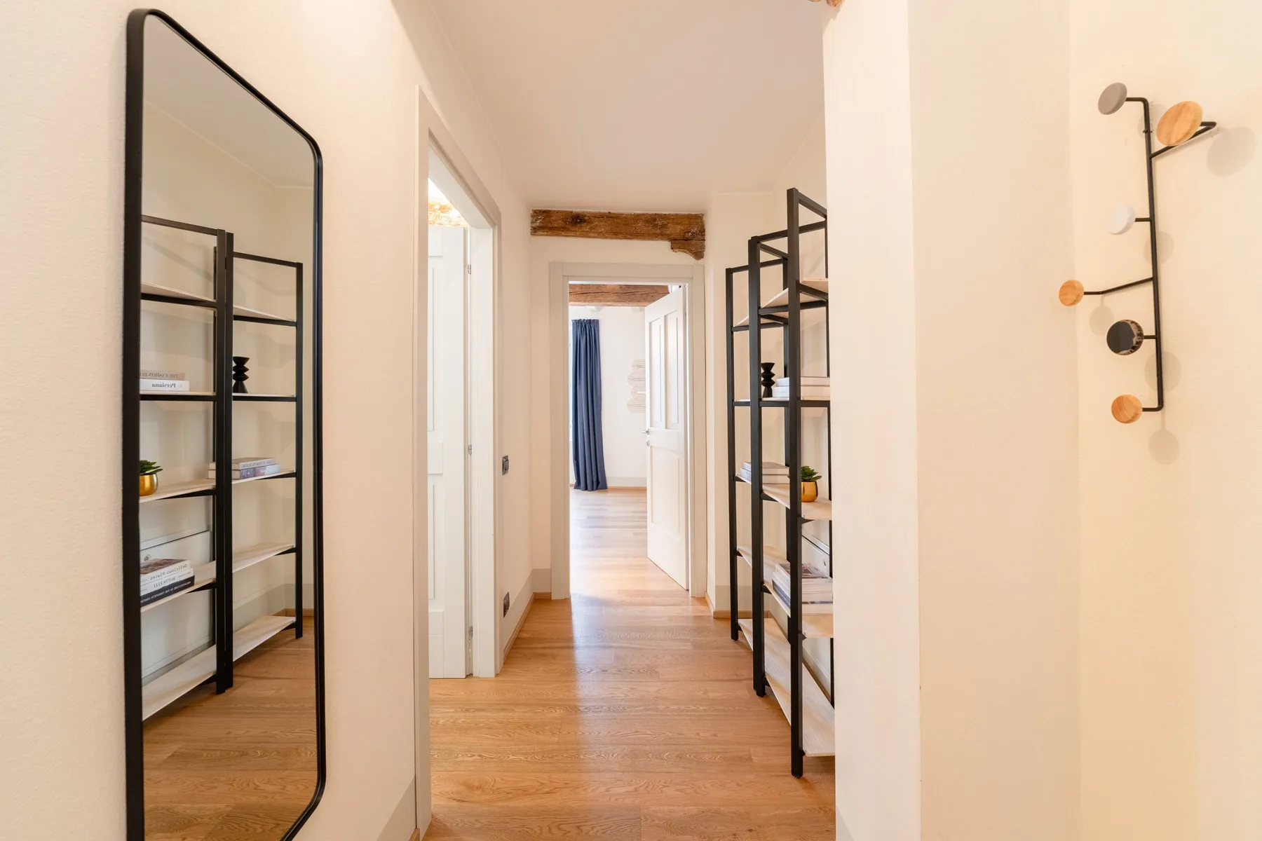 Un pasillo luminoso con suelo de madera y estanterías abiertas a los lados.