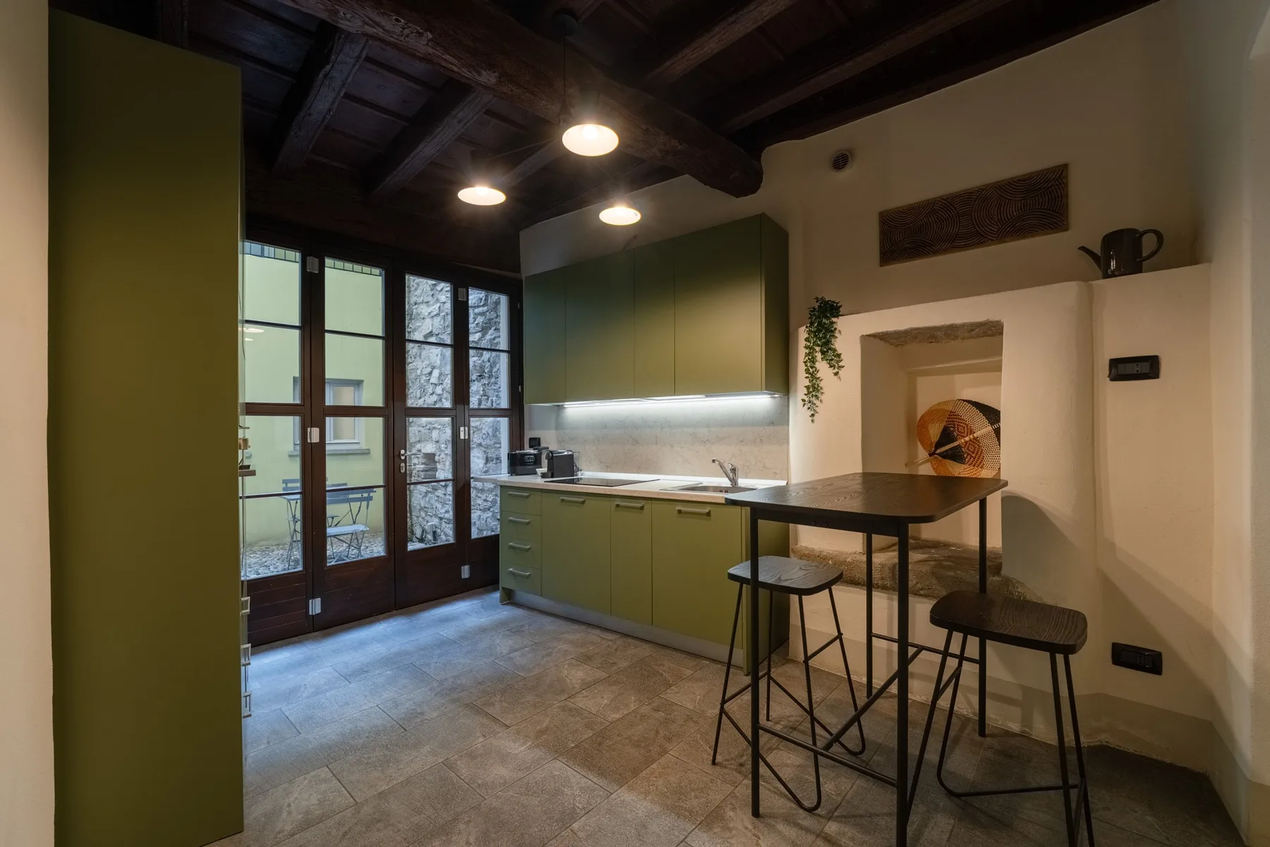 Una cocina compacta con gabinetes verdes, una encimera y una mesa pequeña.