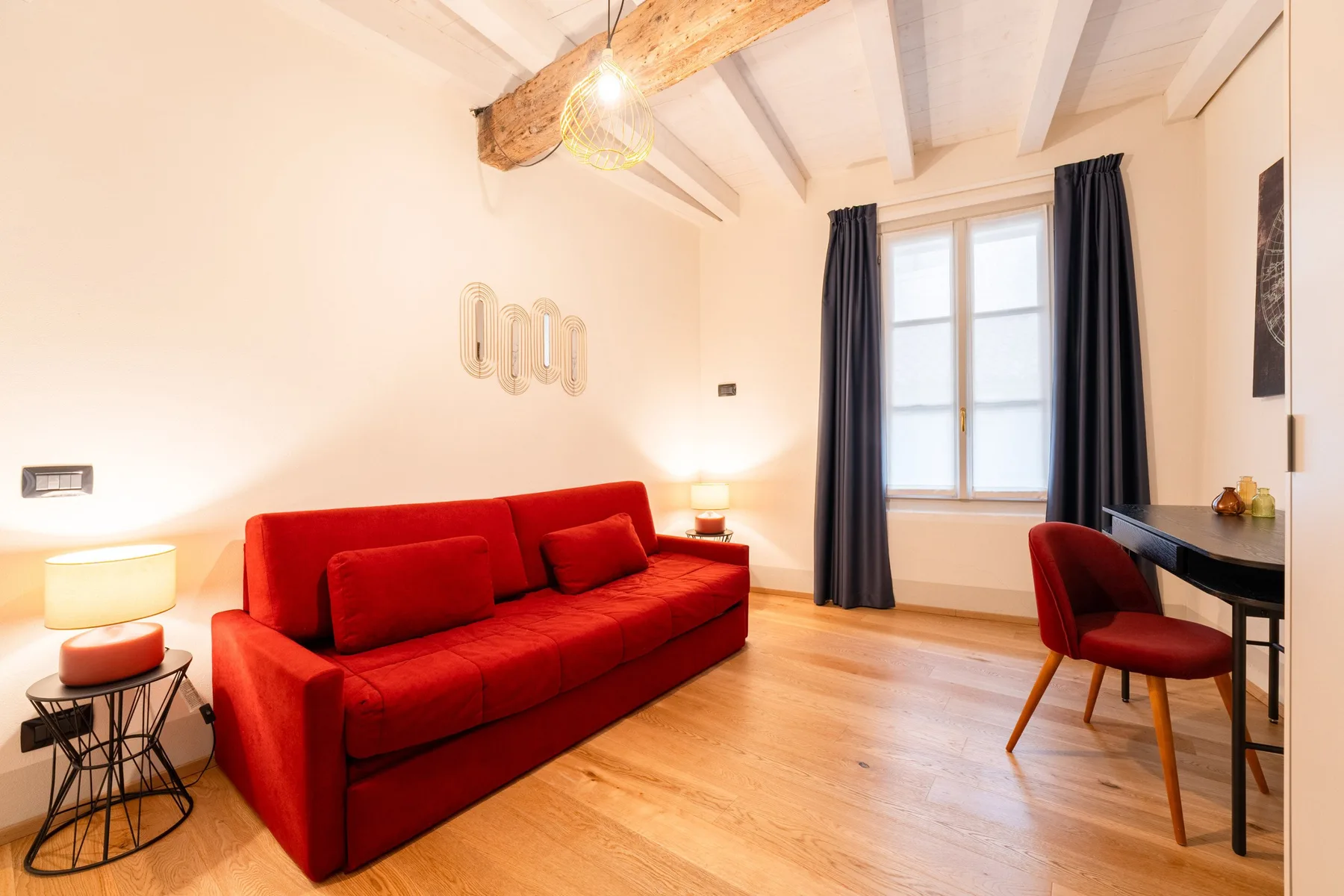 Una luminosa sala de estar con asientos rojos, un escritorio y una ventana.