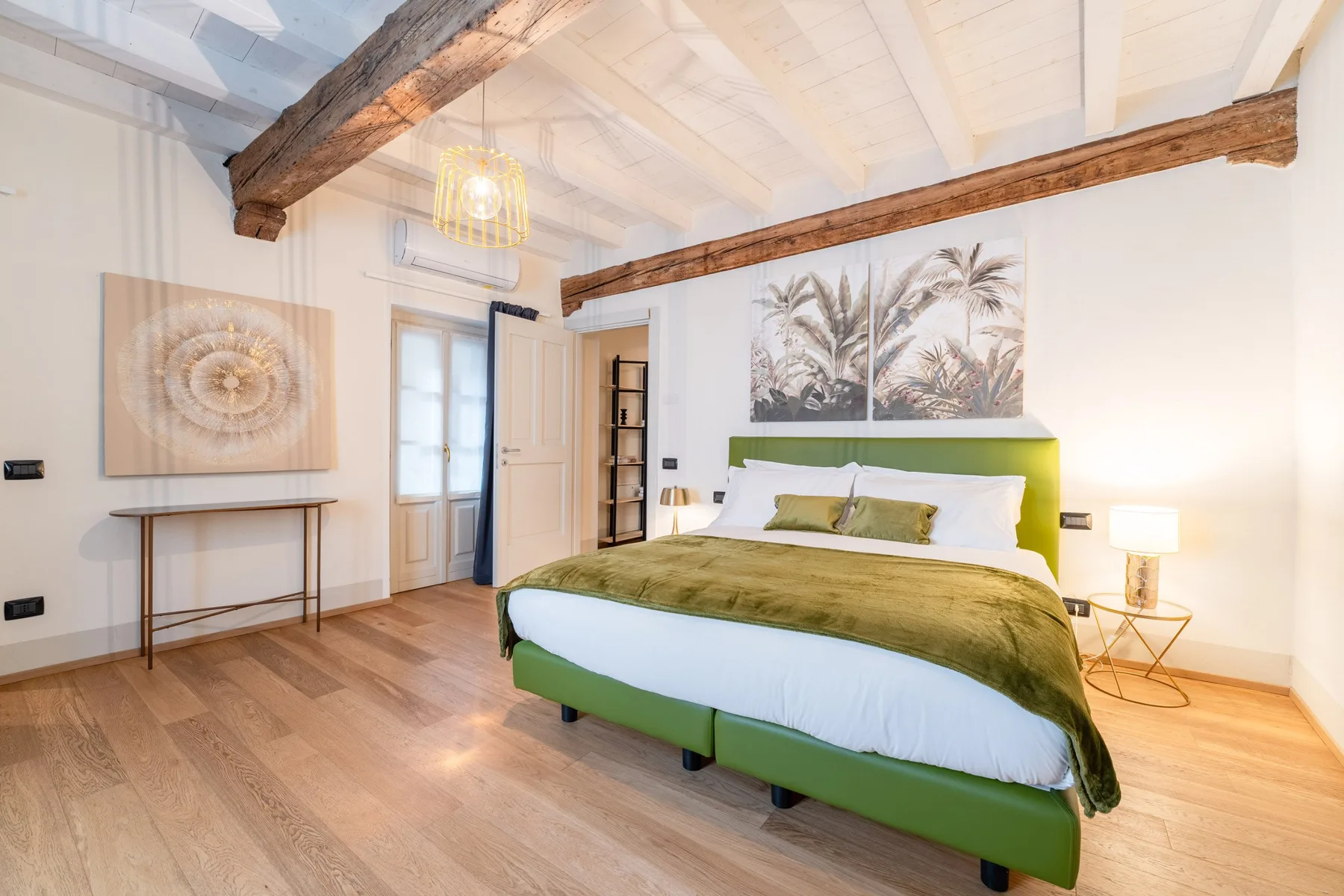 Un dormitorio con una cama verde bajo un cuadro botánico.