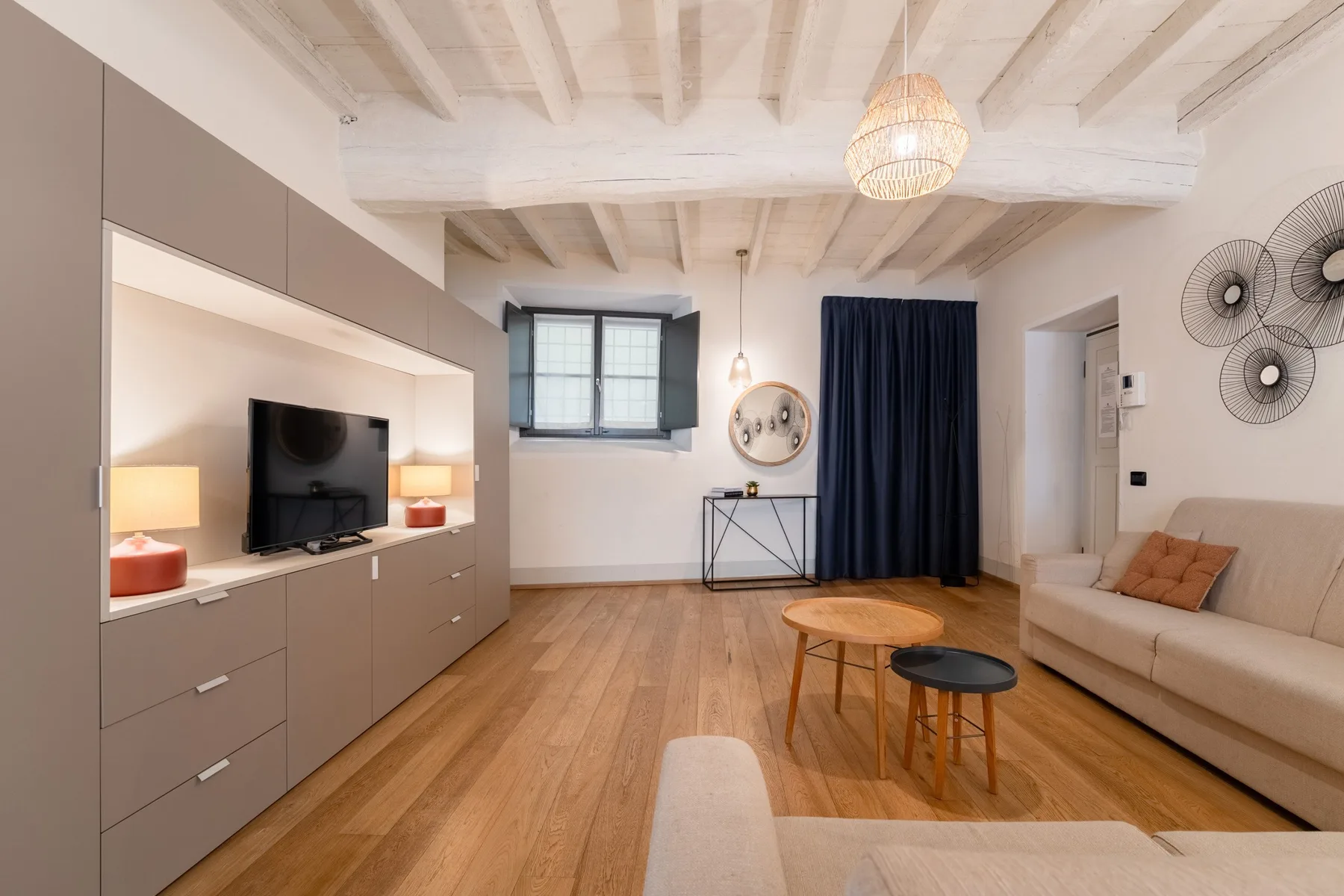 Una sala luminosa con televisor, asientos y una mesa de centro de madera.