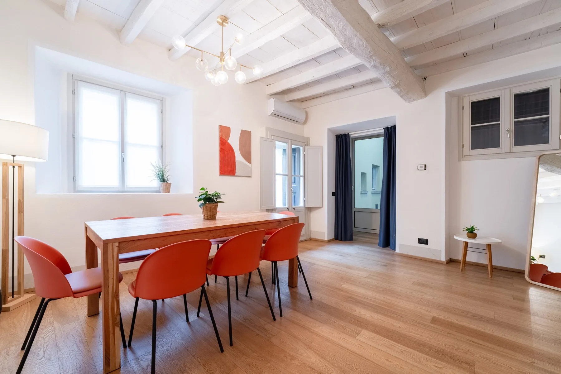 Un comedor luminoso con una mesa larga de madera y asientos rojos.