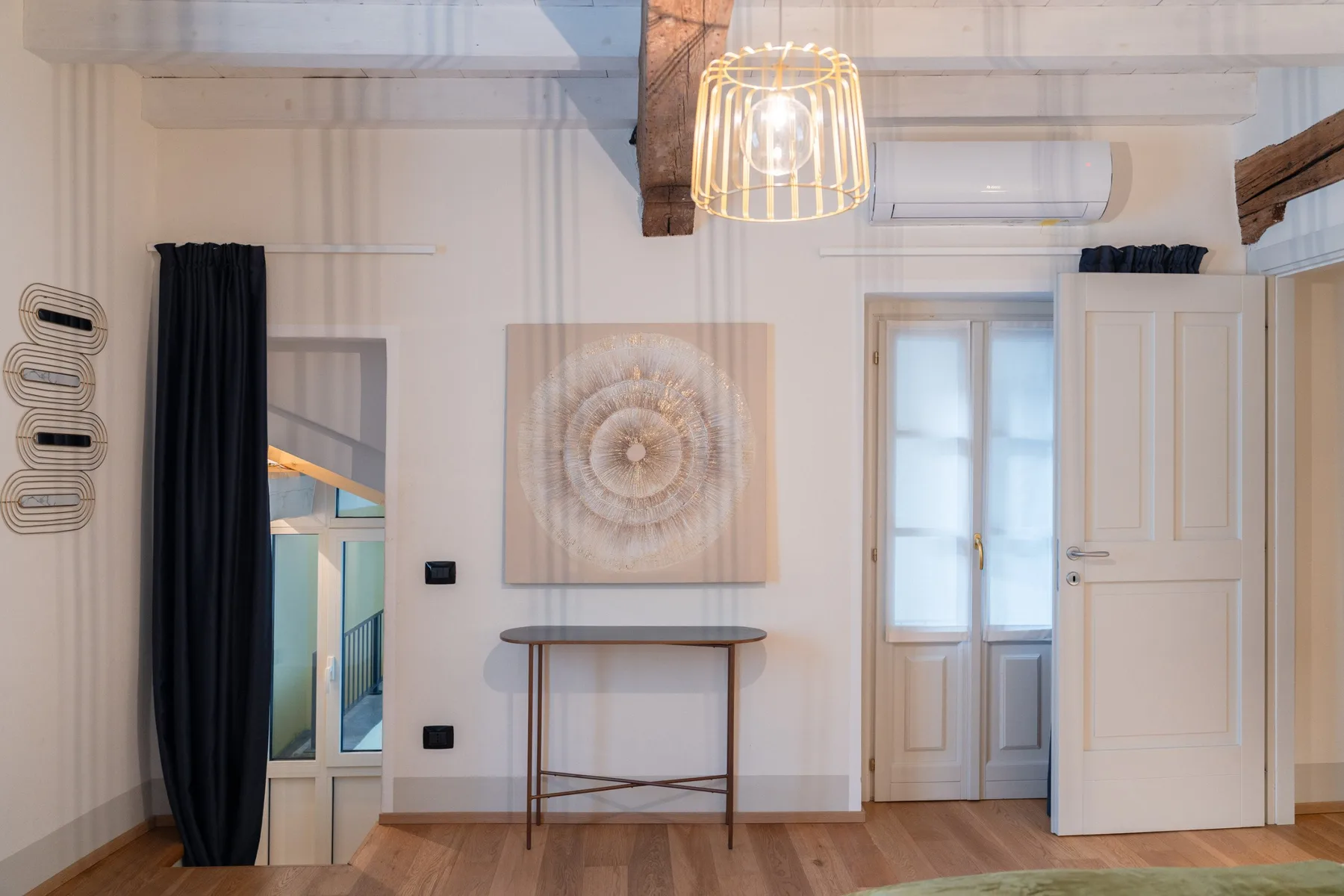 Un dormitorio luminoso con un tapiz, una mesa estrecha y una puerta abierta.