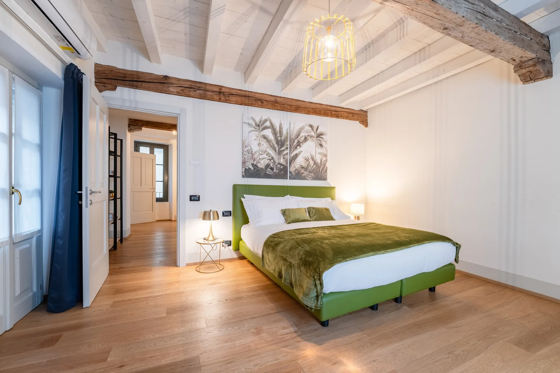 Un dormitorio con una cama verde bajo un techo inclinado con vigas.