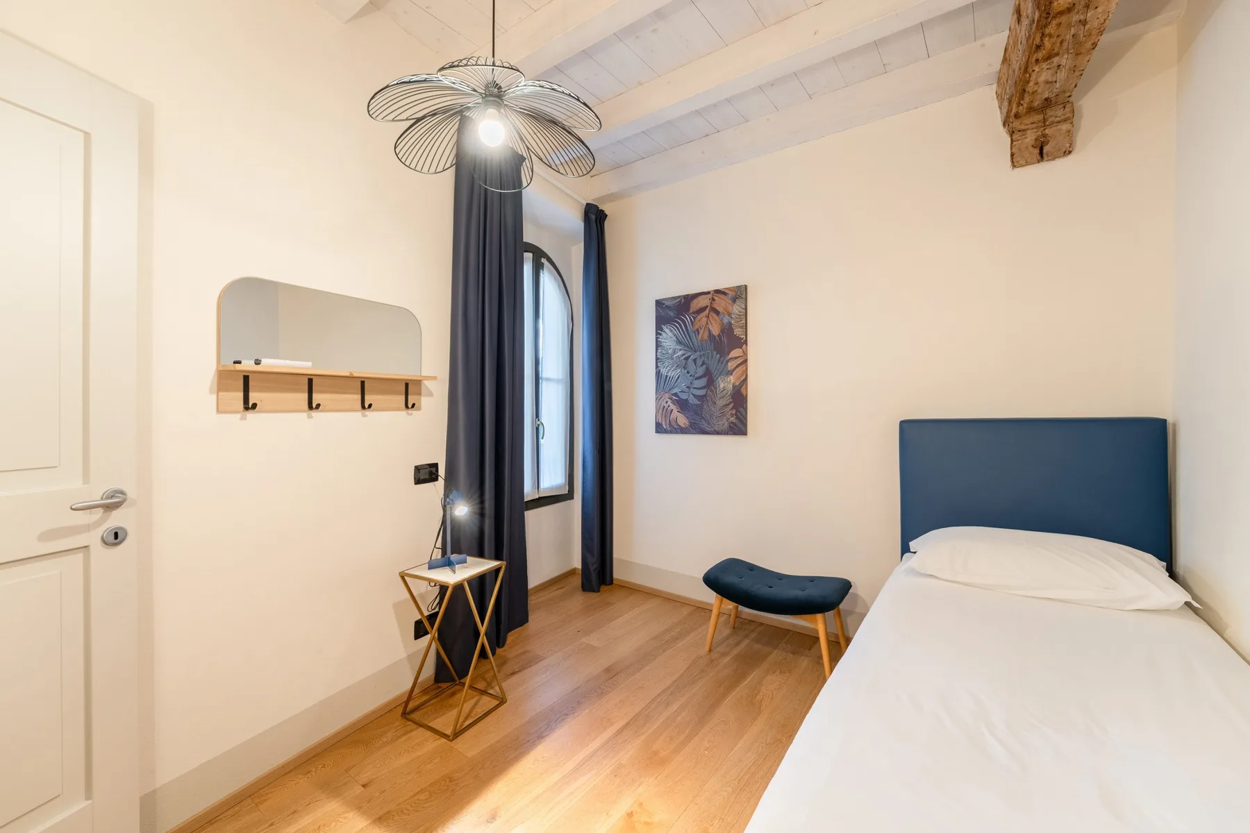 Un dormitorio con una cama individual, una ventana y una pequeña zona de estar.