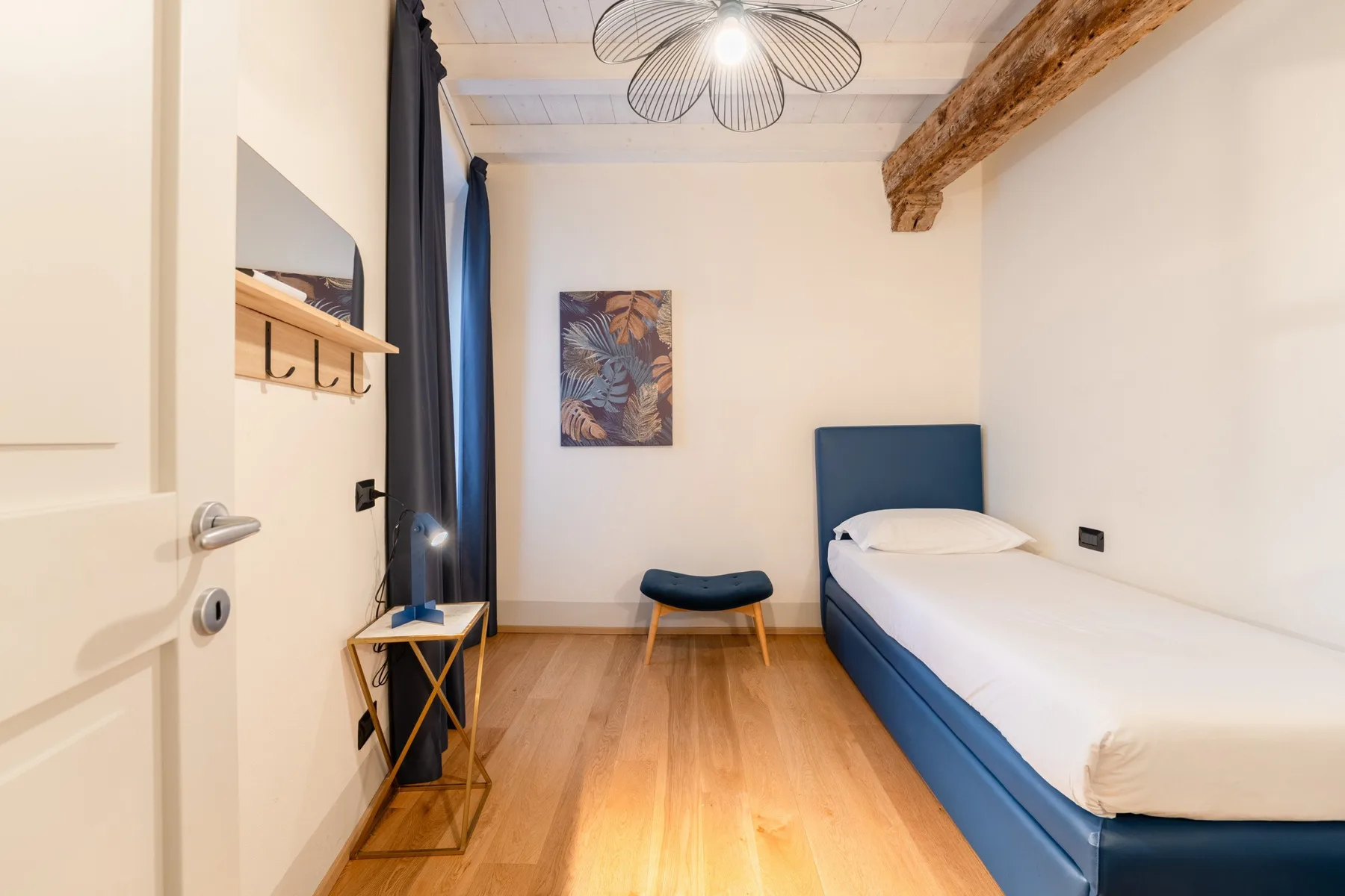 Una habitación con una cama, asientos azules y una mesita junto a la cama.