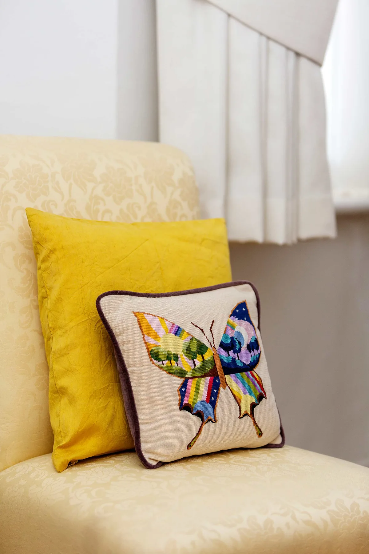 Un asiento estampado tiene un cojín amarillo y otro pequeño con una mariposa bordada.