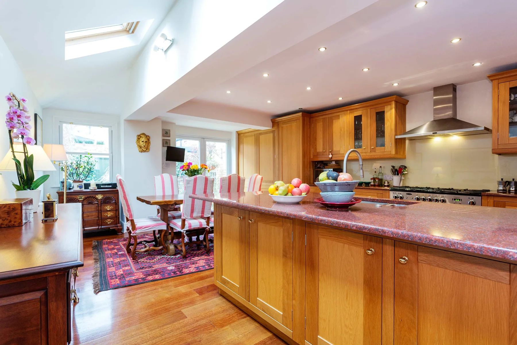 Una cocina luminosa con una isla grande y una mesa de comedor junto a las ventanas.