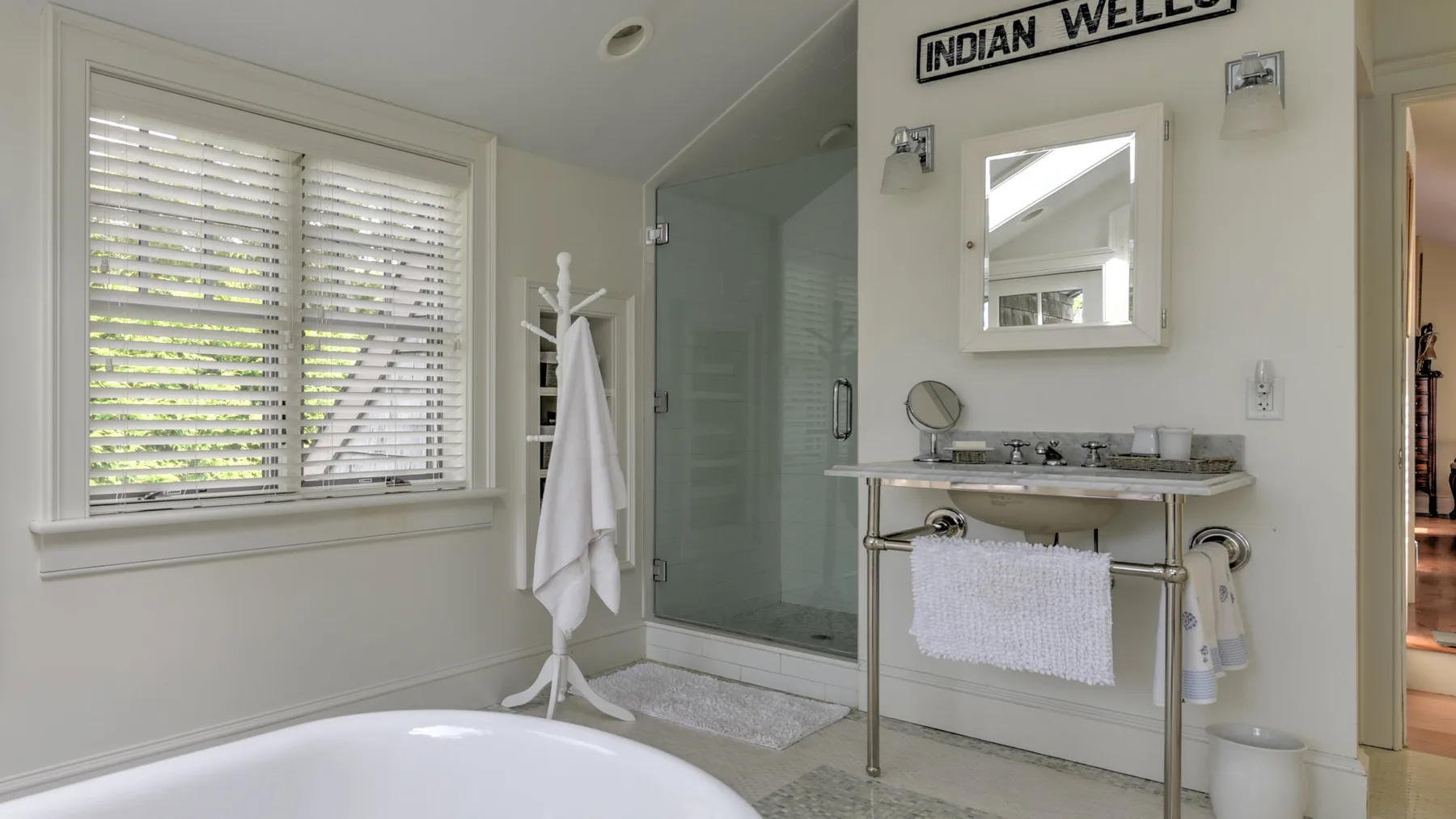 Un baño con bañera, ducha de vidrio y lavabo bajo un espejo.