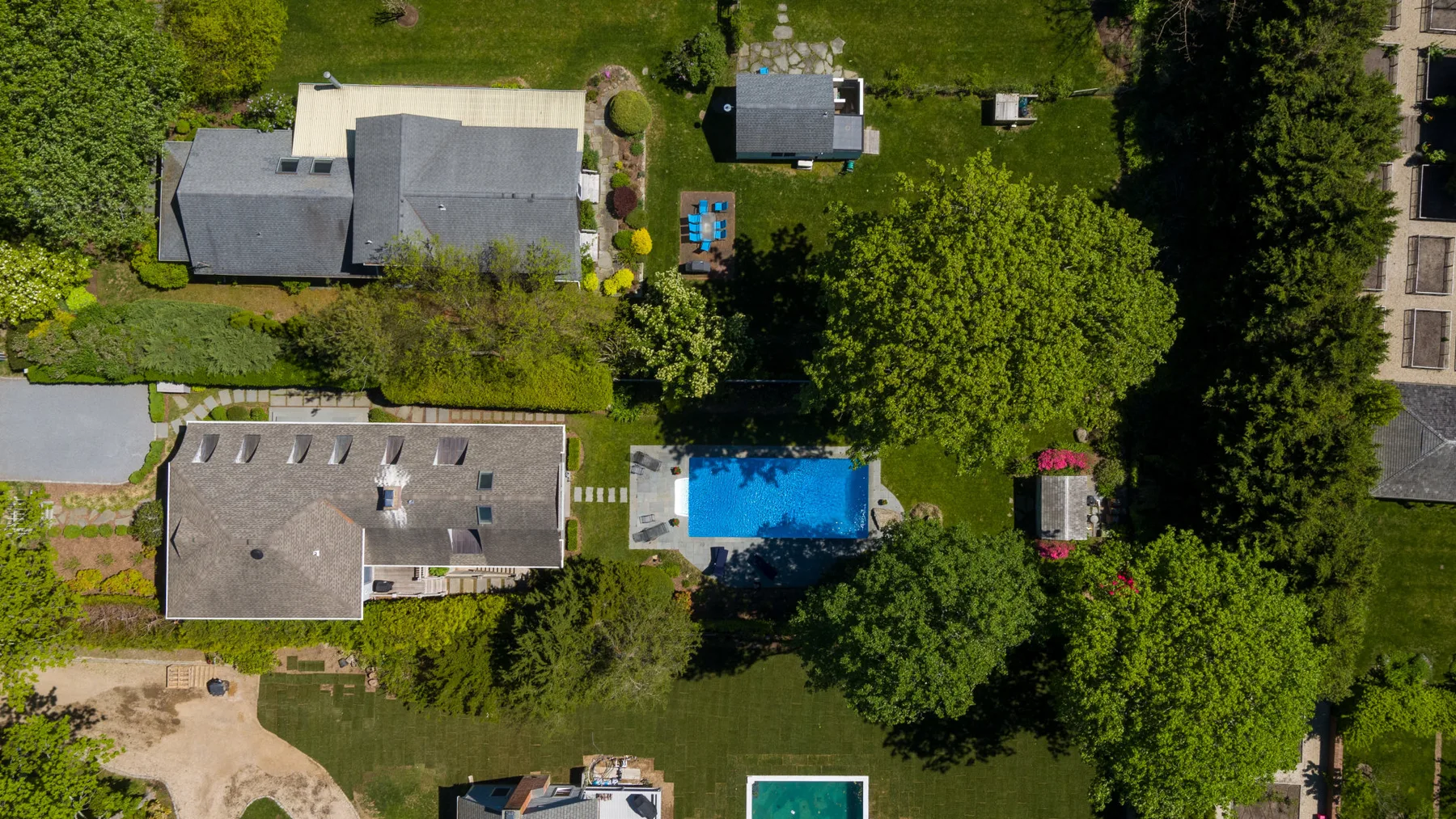 Vista aérea de varios edificios y una piscina azul entre árboles.