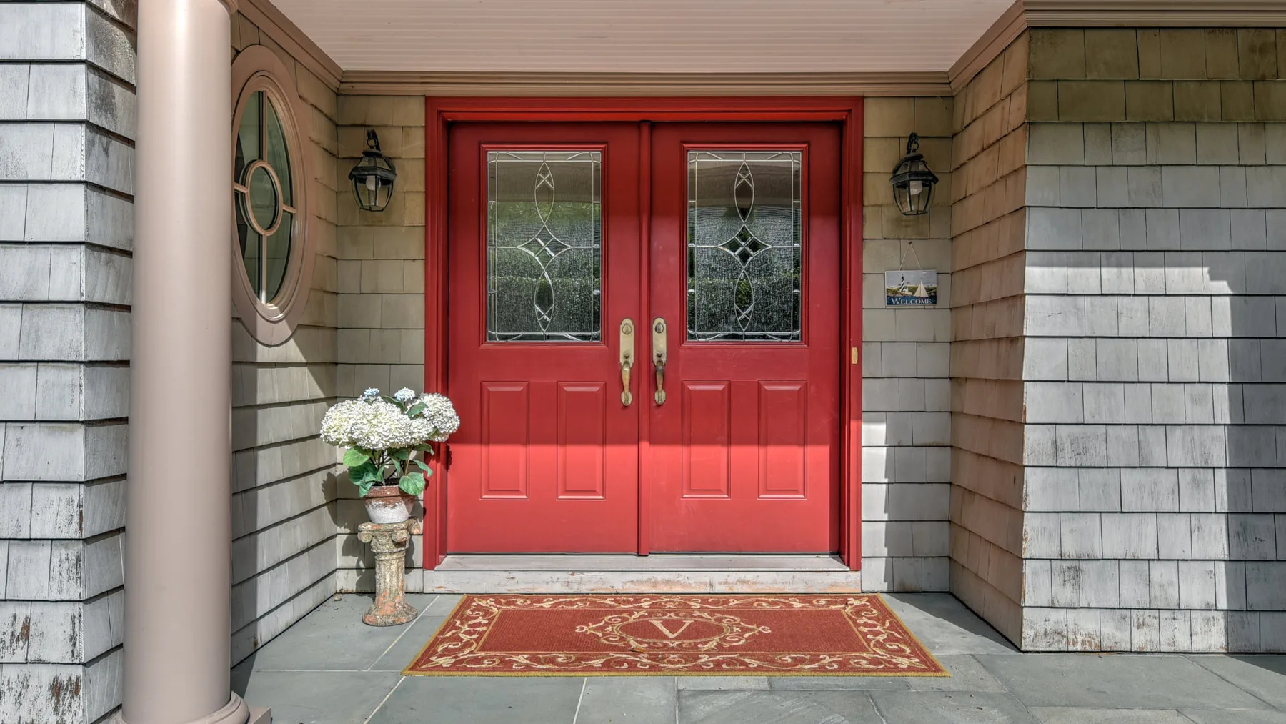 Una entrada cubierta con puertas dobles rojas y un tapete estampado.