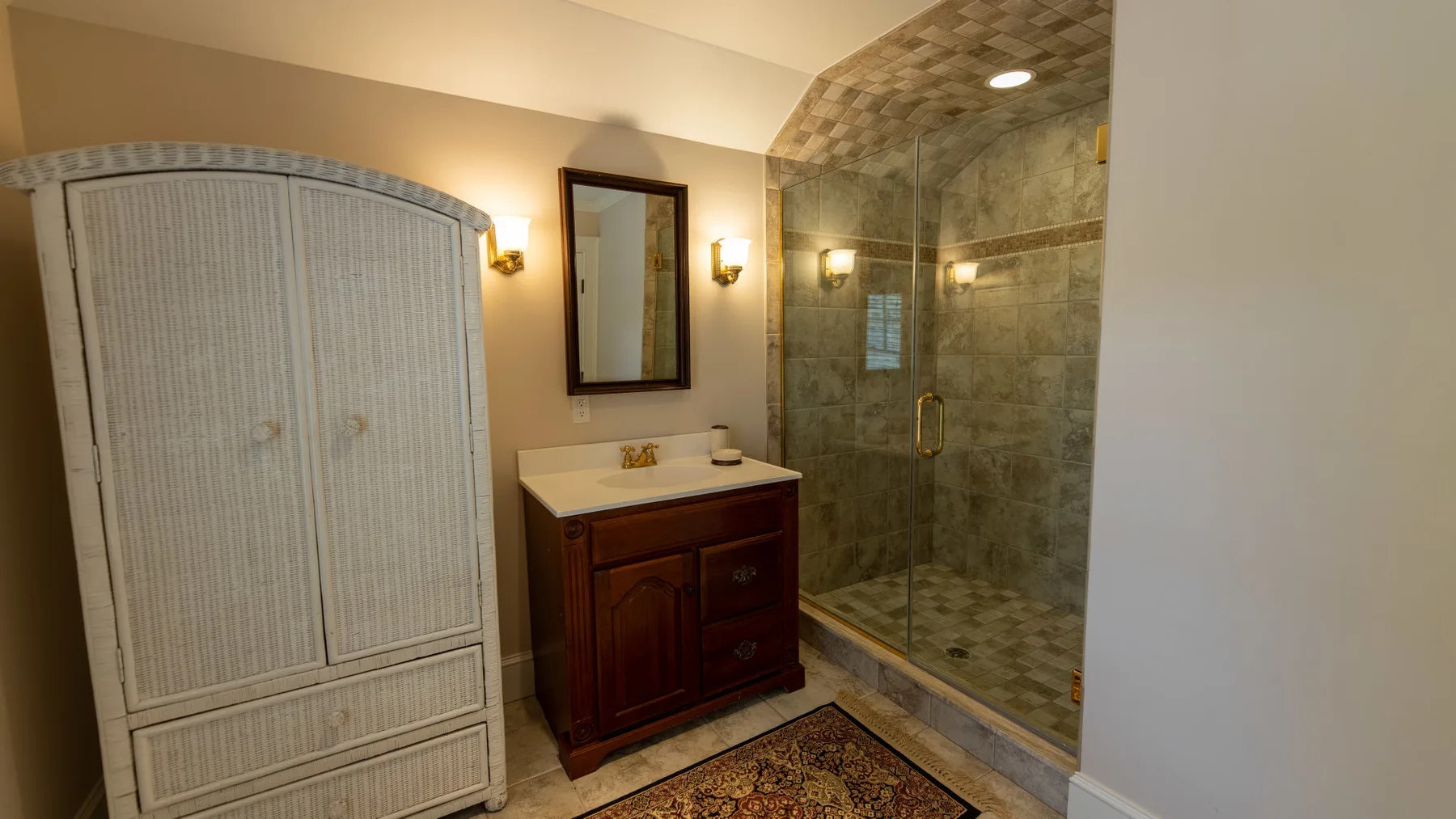 Un baño con lavabo, espejo y ducha con mampara de vidrio.