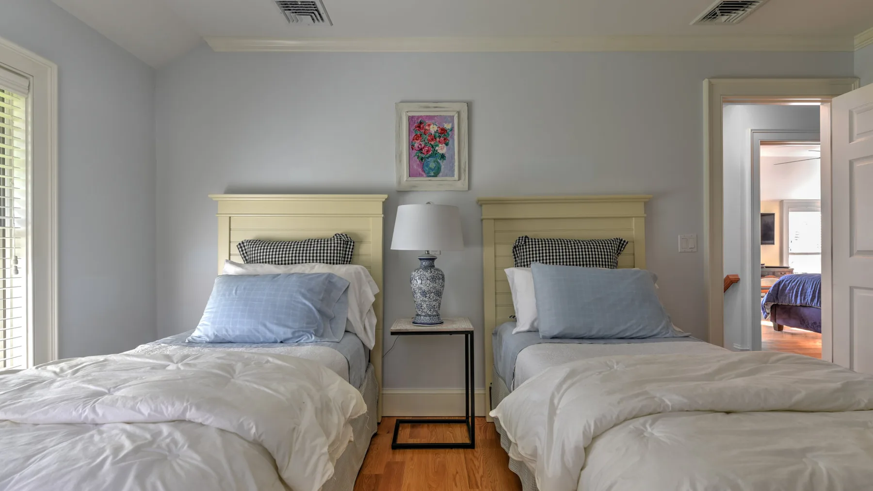 Un dormitorio con dos camas y un cuadro floral en la pared.