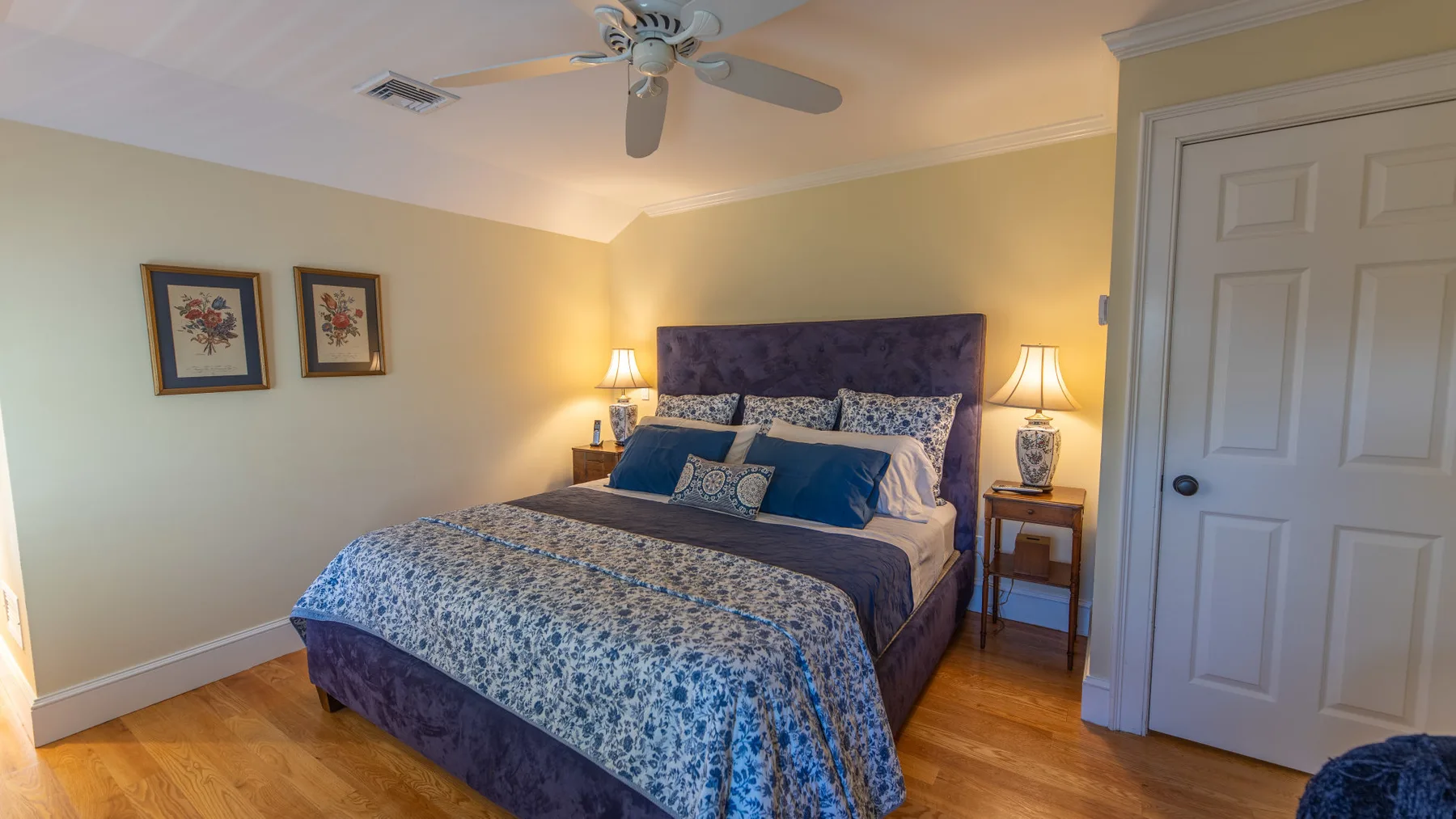 Dormitorio con una cama vestida con ropa de cama azul estampada y mesas de noche a juego.