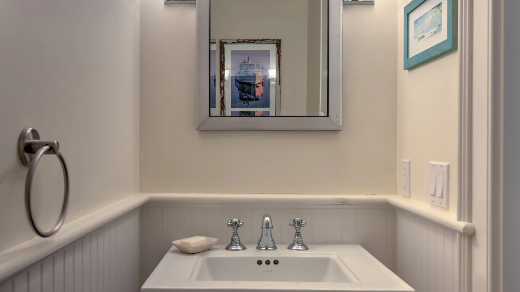 Un lavabo de baño con espejo de pared y aro para toalla.