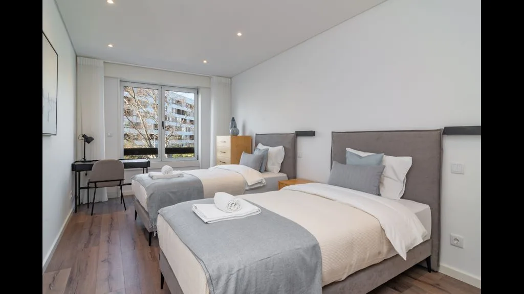 Un dormitorio luminoso con dos camas y una ventana grande.