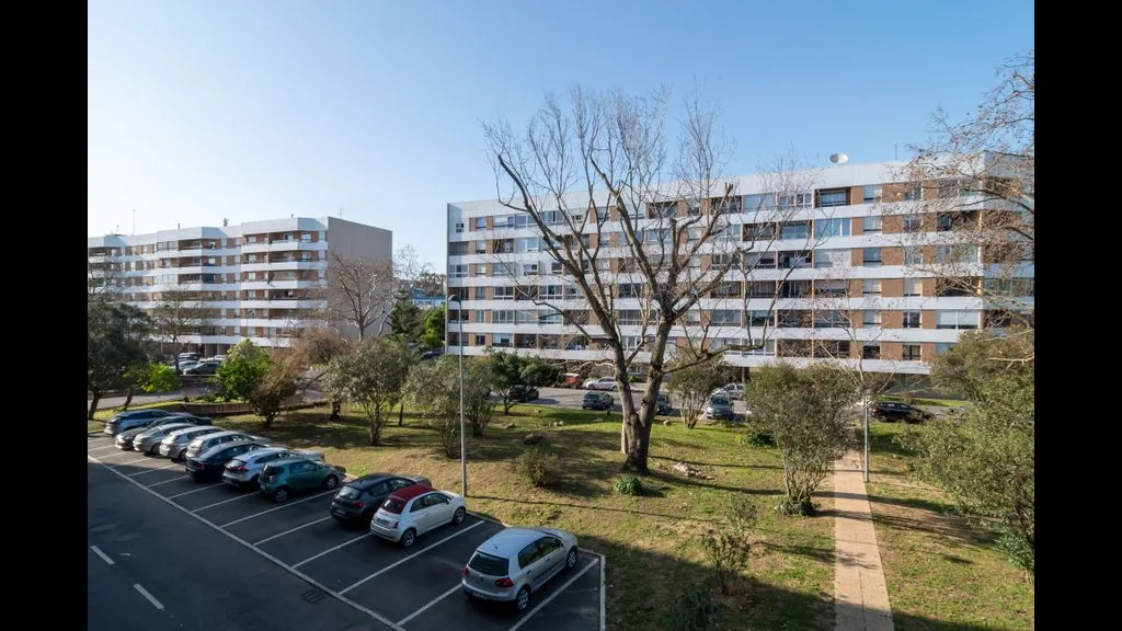 Edificios residenciales dan a un área de estacionamiento y jardines.