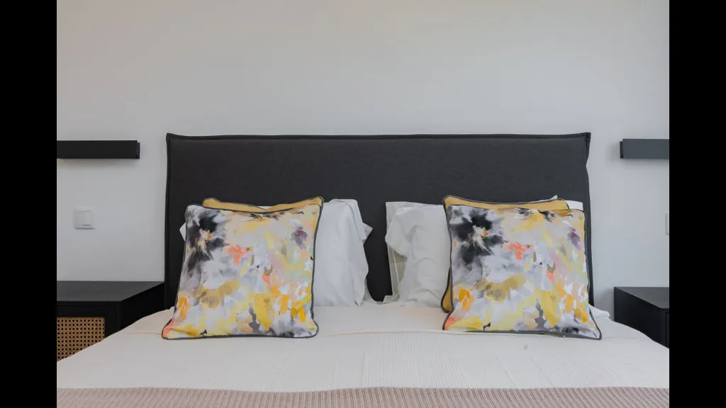Dormitorio con una cama y cojines florales de colores.