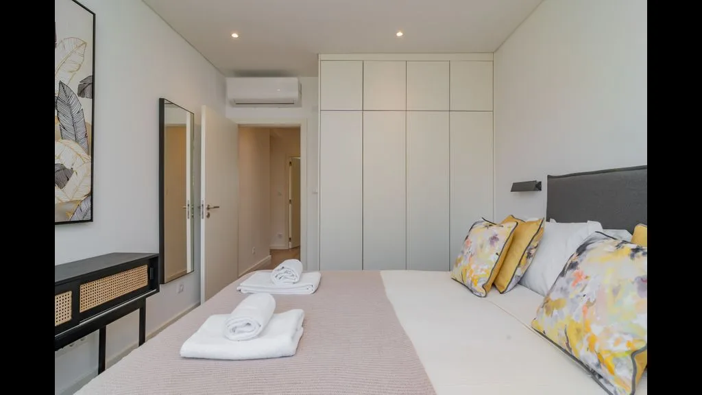 Un dormitorio luminoso con una cama bien hecha y armarios empotrados.