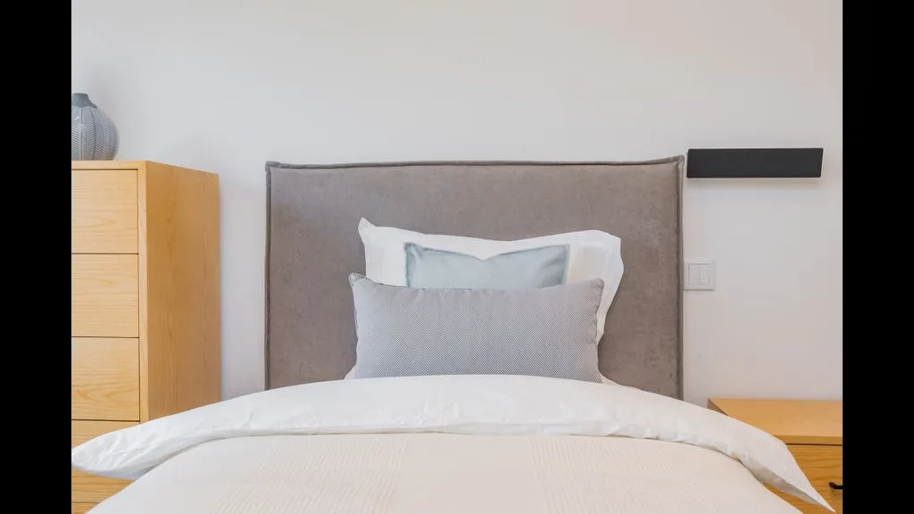 Un dormitorio con una cama bien tendida y ropa de cama clara.