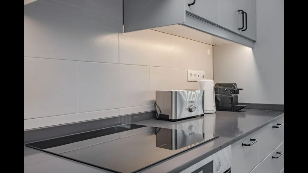 Una encimera de cocina moderna con placa de cocción, tostadora y cafetera.
