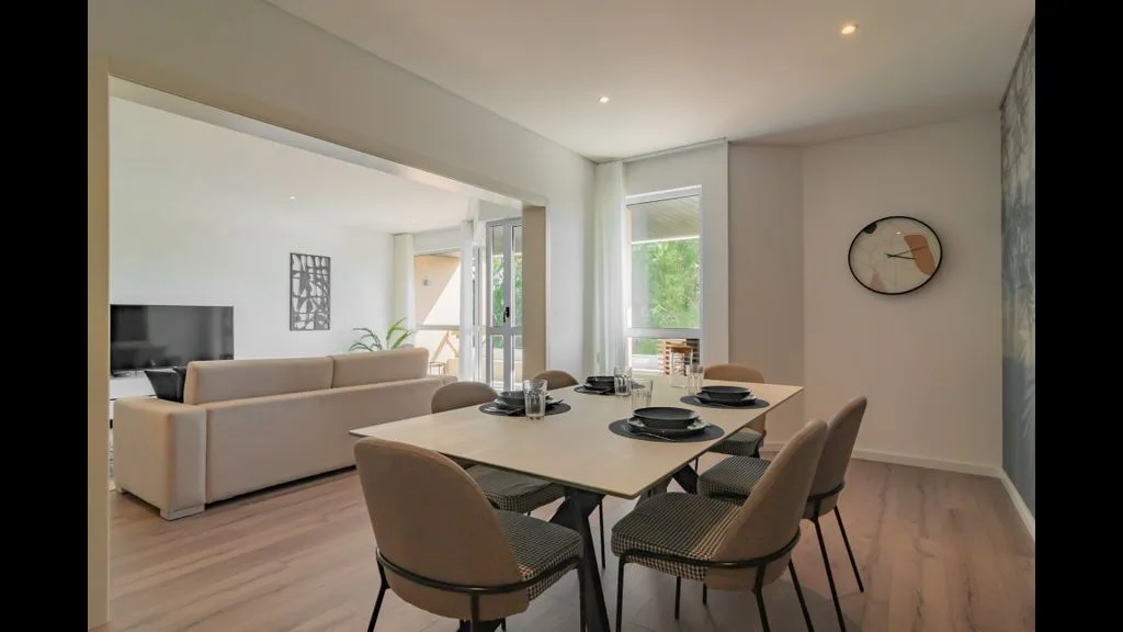 Un comedor con mesa y asientos se abre a una sala de estar.