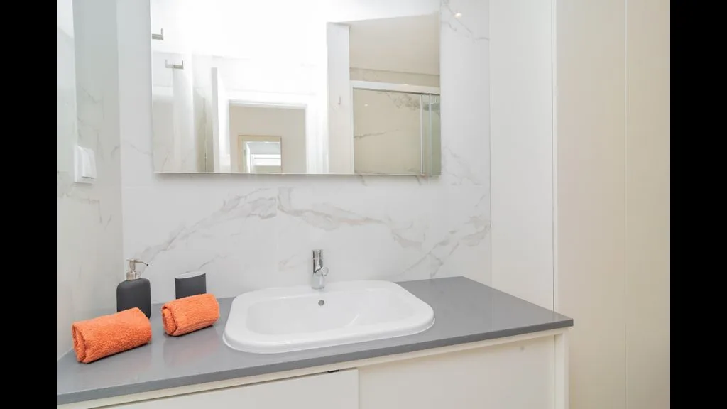 Un lavabo de baño con un lavamanos blanco bajo un espejo grande.
