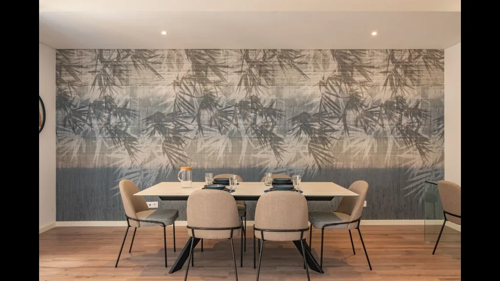 Comedor con una mesa y sillas frente a una pared estampada.