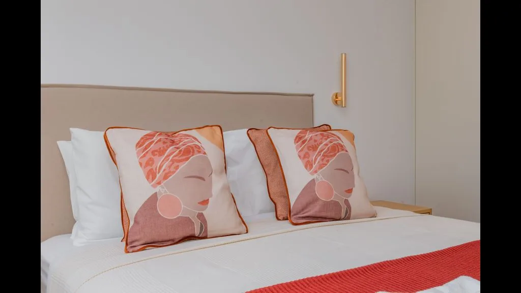 Un dormitorio con una cama tendida y dos almohadas estampadas.