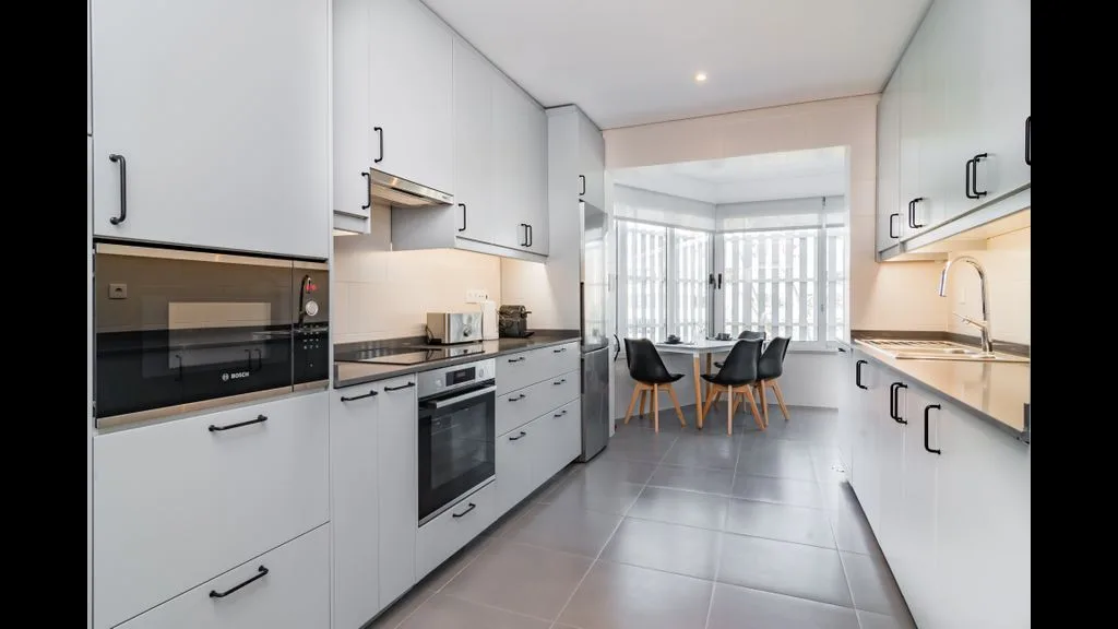 Una cocina moderna y luminosa con una isla y asientos junto a grandes ventanales.