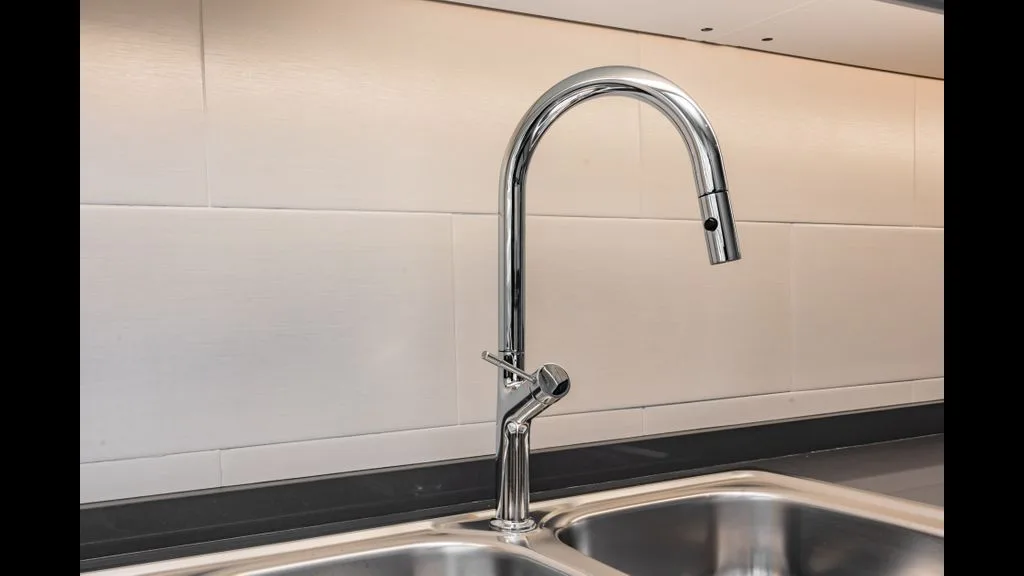 Un fregadero de cocina con un grifo curvo frente a una pared de azulejos.