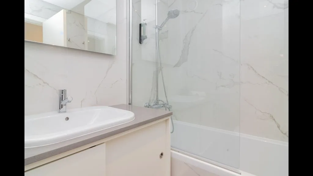 Un baño con lavabo y ducha de vidrio.