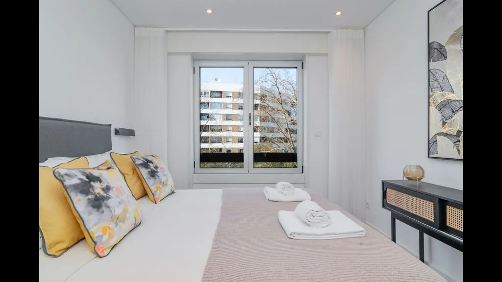 Un dormitorio luminoso con una cama junto a una ventana grande.