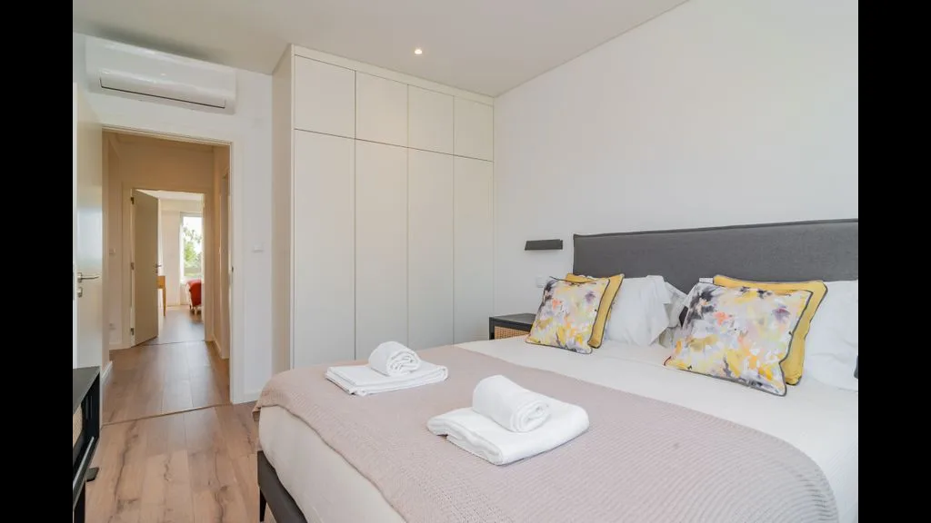 Un dormitorio con una cama doble, cojines coloridos y armarios empotrados.