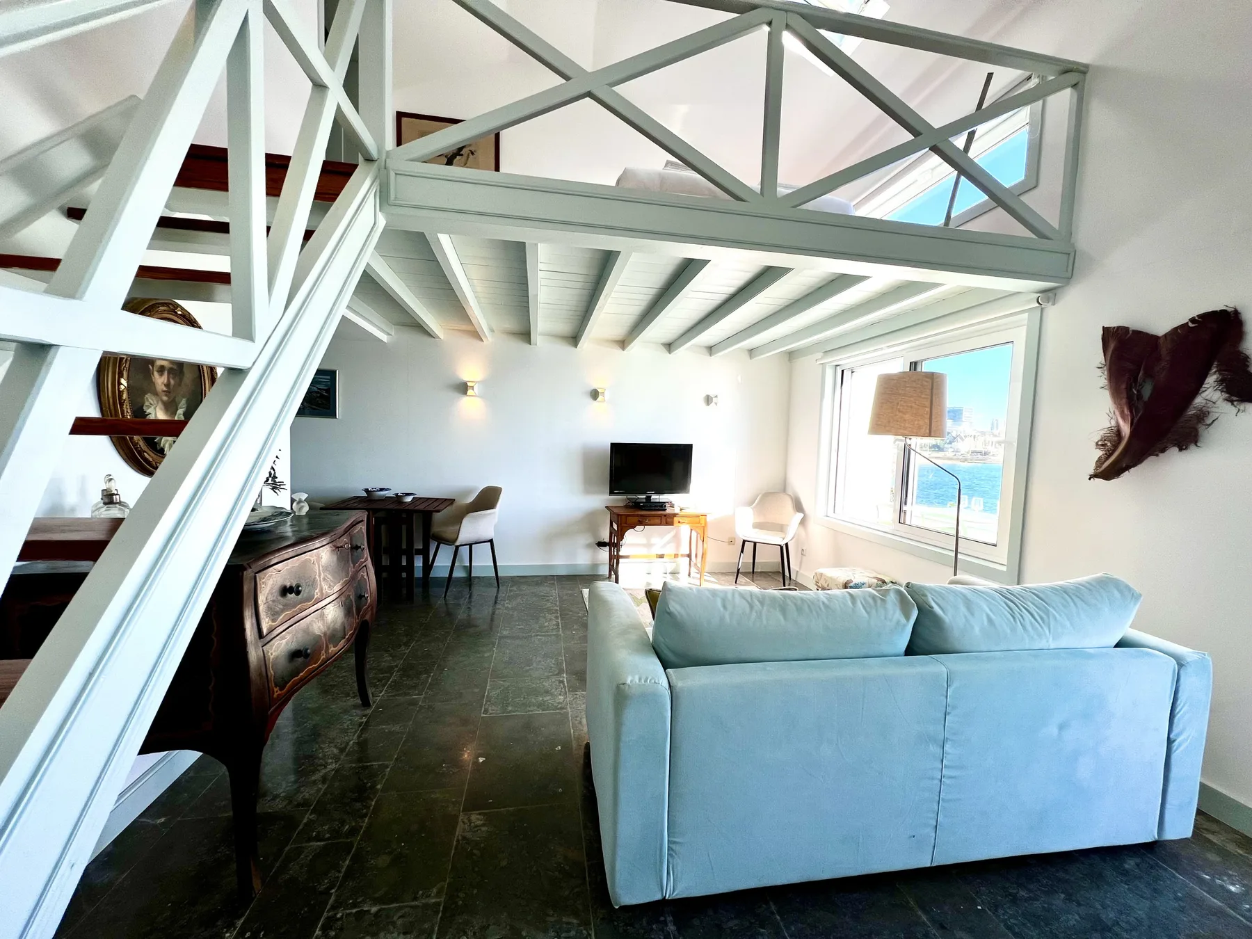 A bright living room with seating, a dining area, and large windows.
