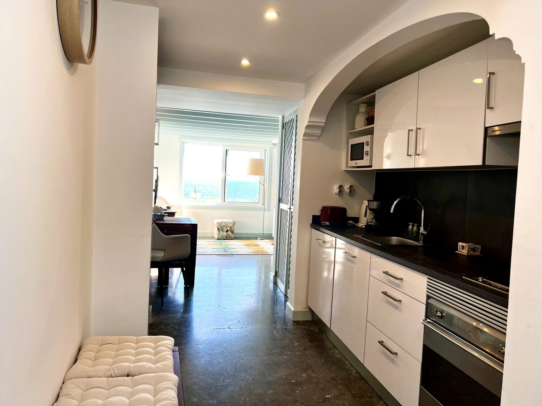 A compact kitchen opens into a dining area beside a bright window.