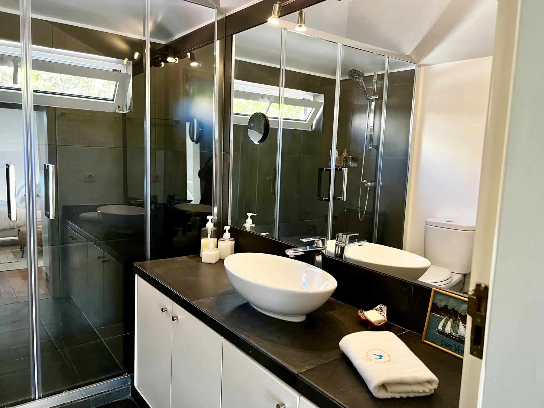 A bathroom with a glass shower and a white vessel sink.