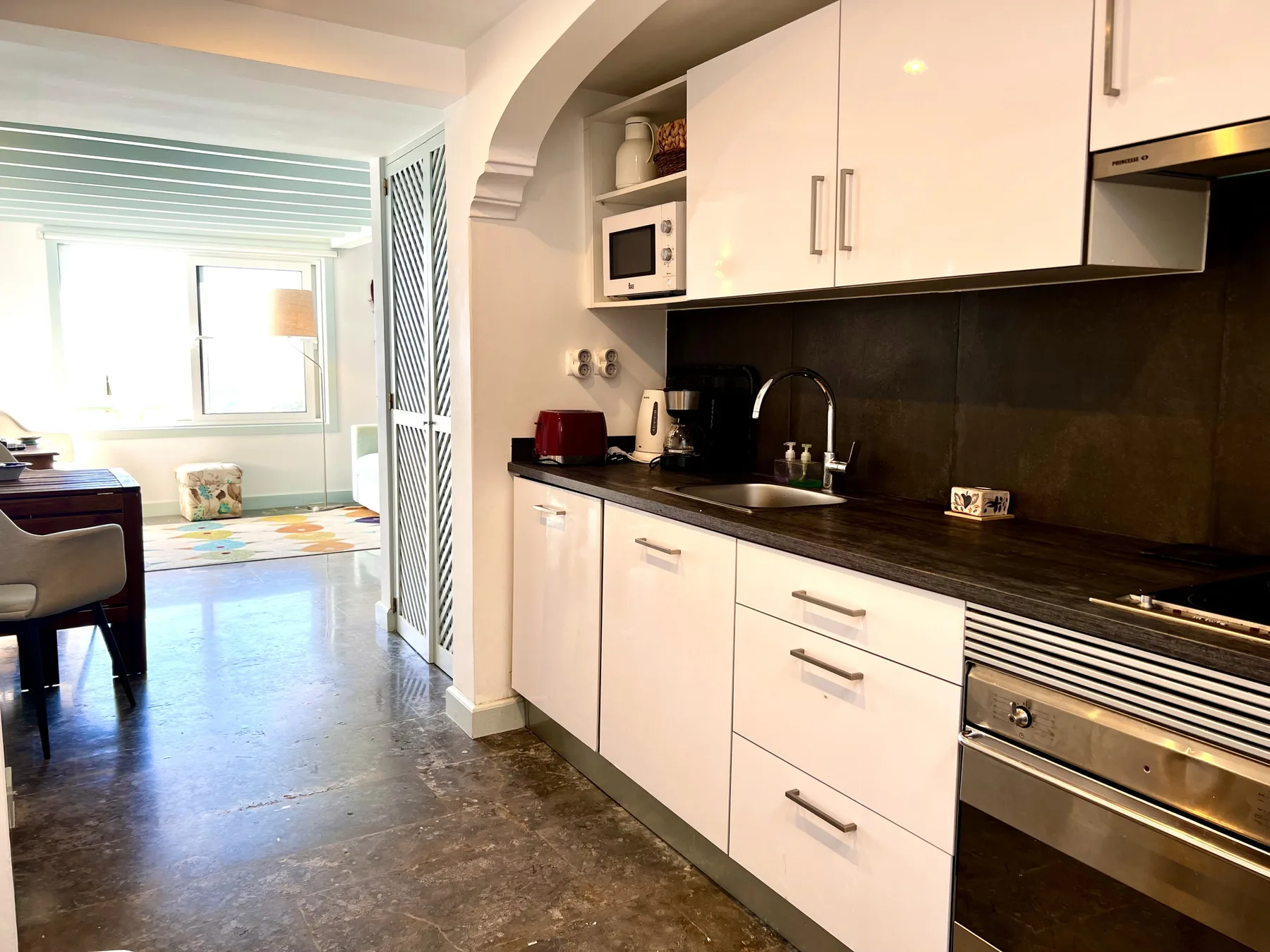 A bright kitchen opens onto a sunlit living area.