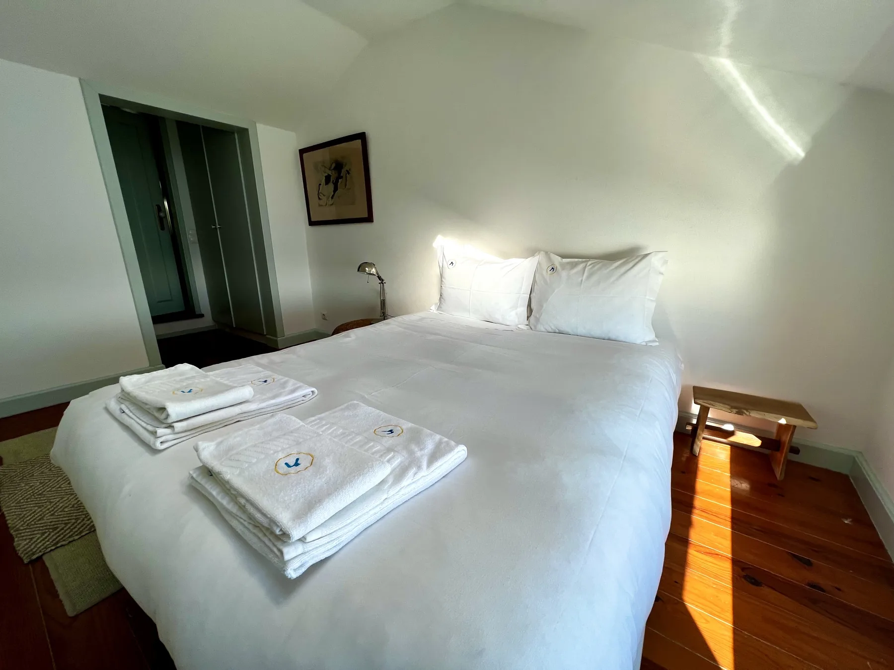 A bedroom with a neatly made bed and folded towels.