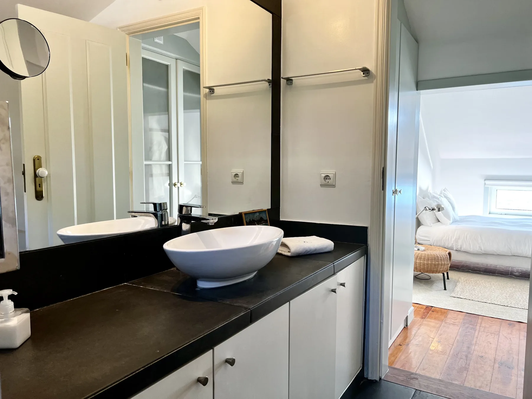 A bathroom vanity with a vessel sink and a bedroom visible through the doorway.