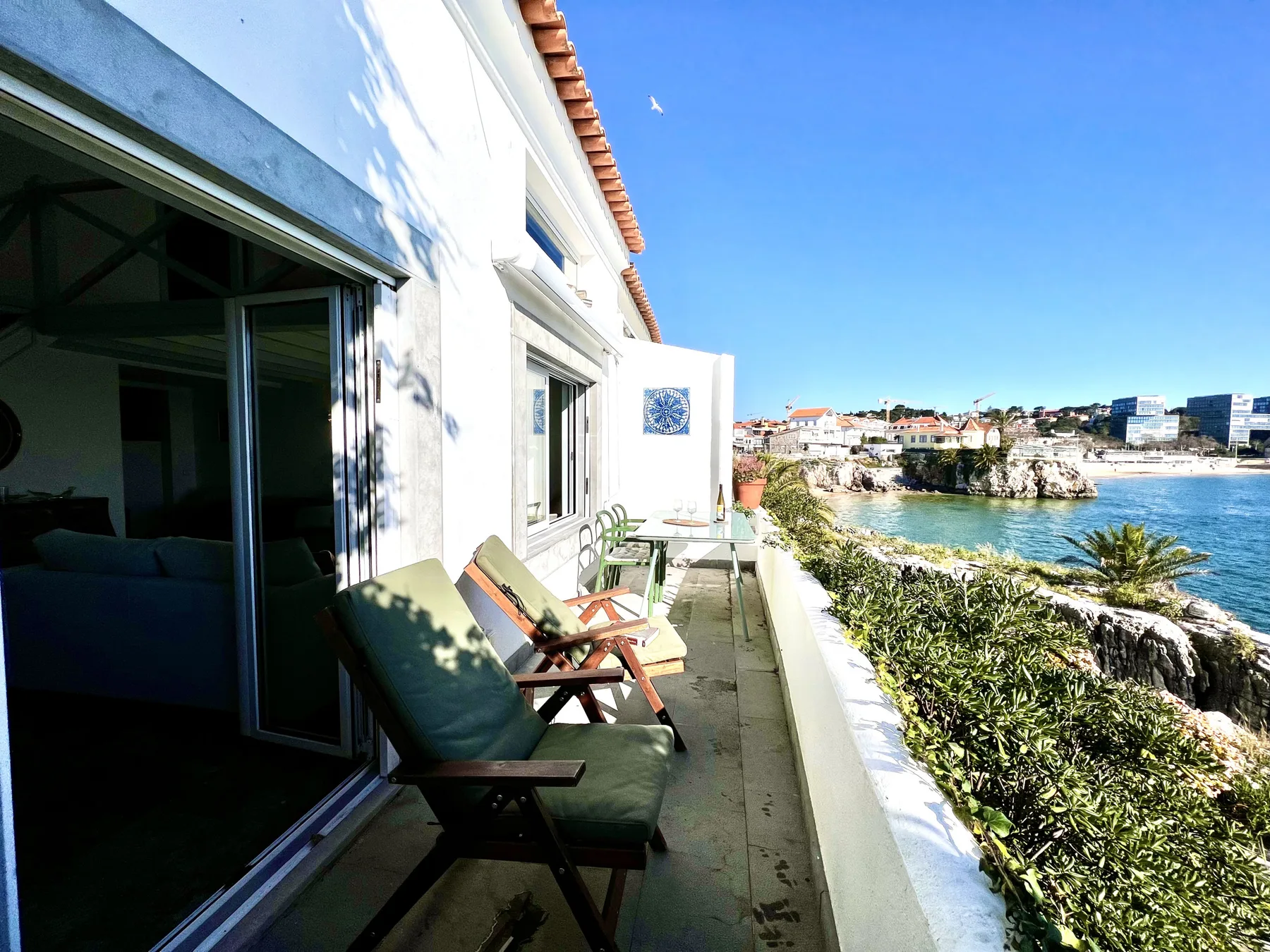 A seaside balcony overlooks the rocky coastline and blue water.