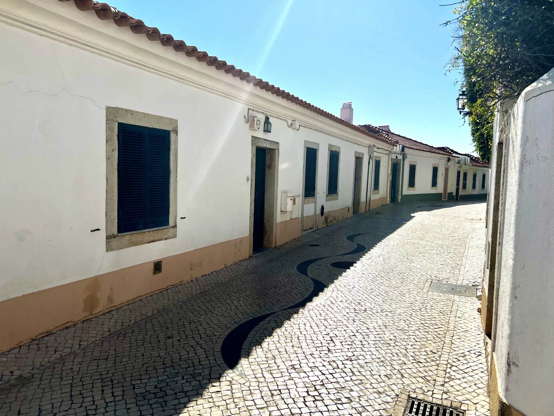 A narrow cobbled street lined with white buildings and dark shutters.