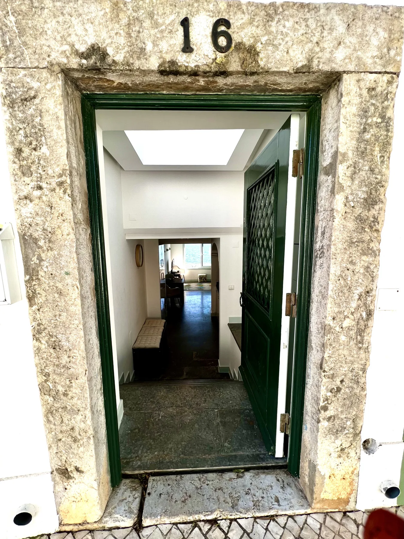 An open green doorway leads into a bright interior hallway.